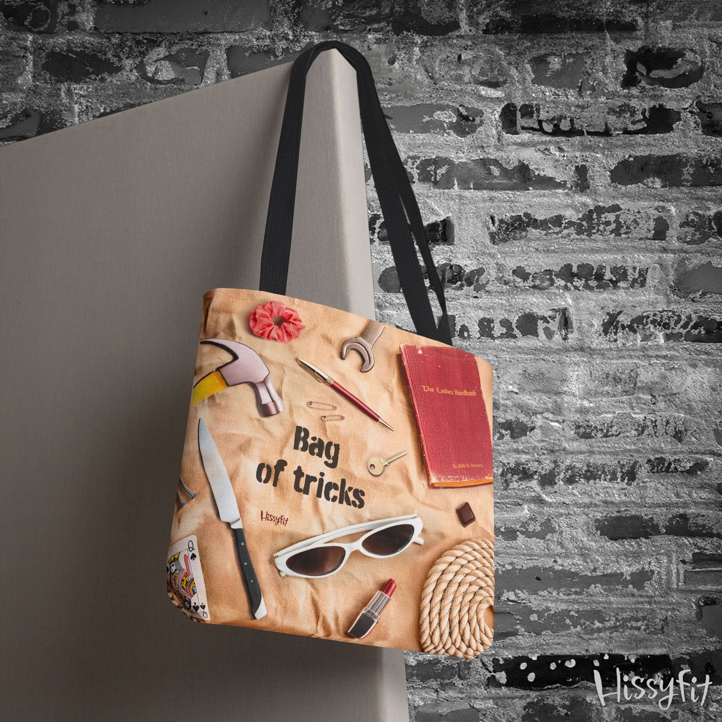 Tote bag with various items and text 'Bag of tricks' against a textured wall background