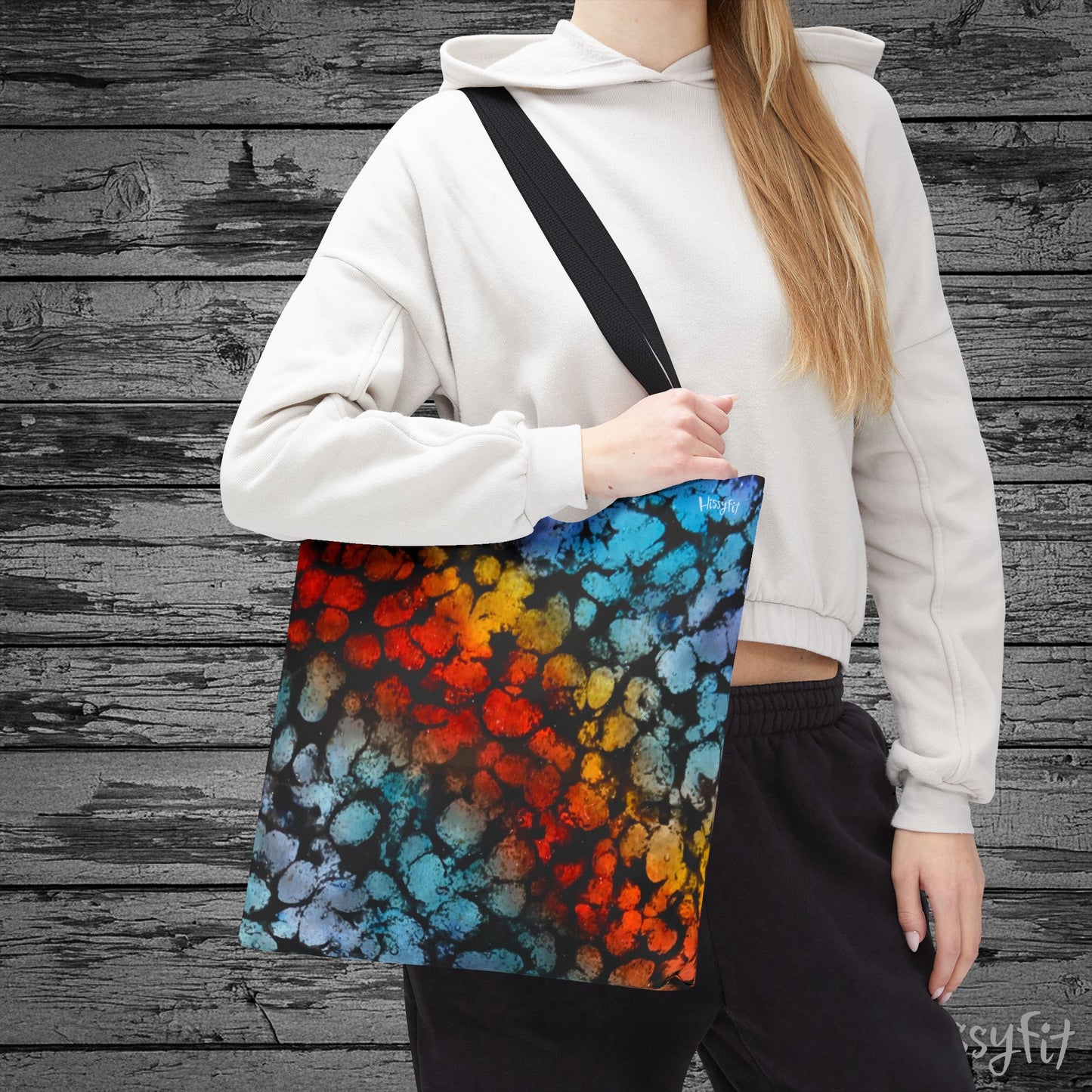 Person holding a colorful tote bag against a wooden background