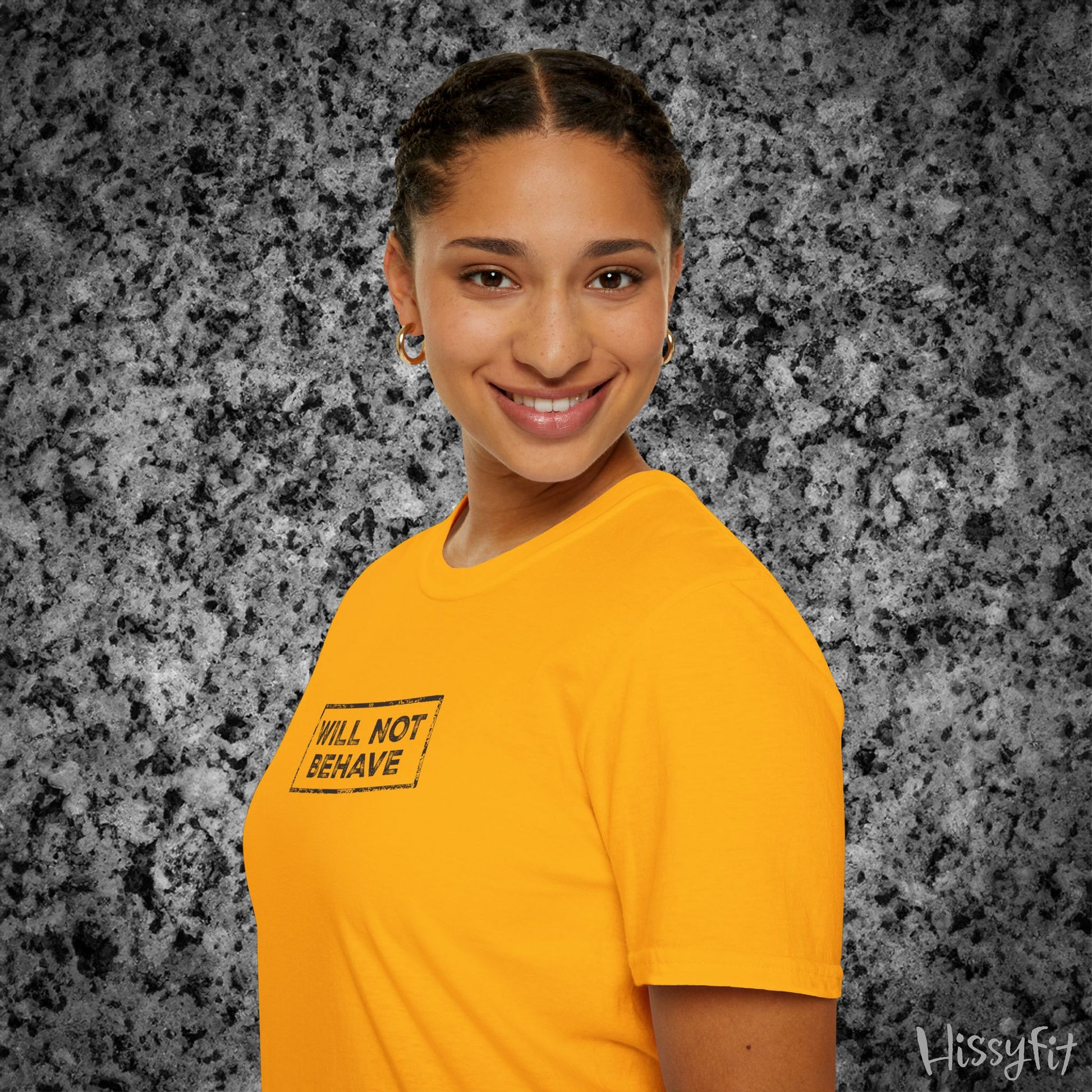 Person wearing a yellow t-shirt with 'WILL NOT BEHAVE' text on a gray textured background