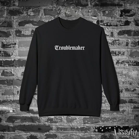 Black sweatshirt with 'Troublemaker' text on a stone wall background