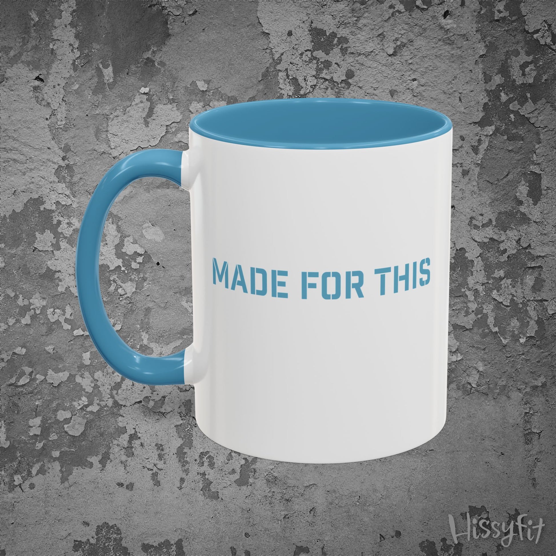 White mug with blue interior and handle on a textured gray background, featuring 'MADE FOR THIS' text.