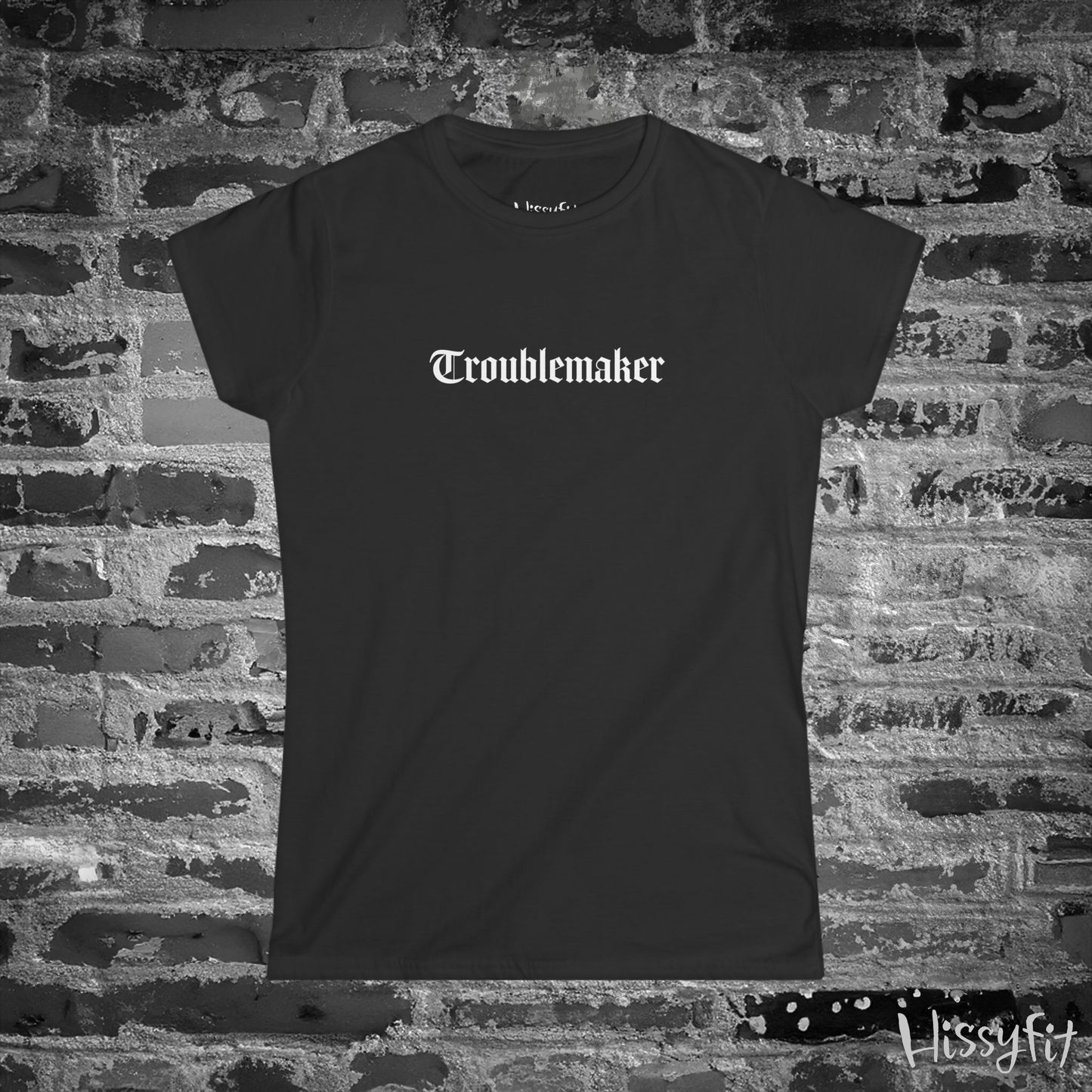 Black t-shirt with 'Troublemaker' text on a brick wall background