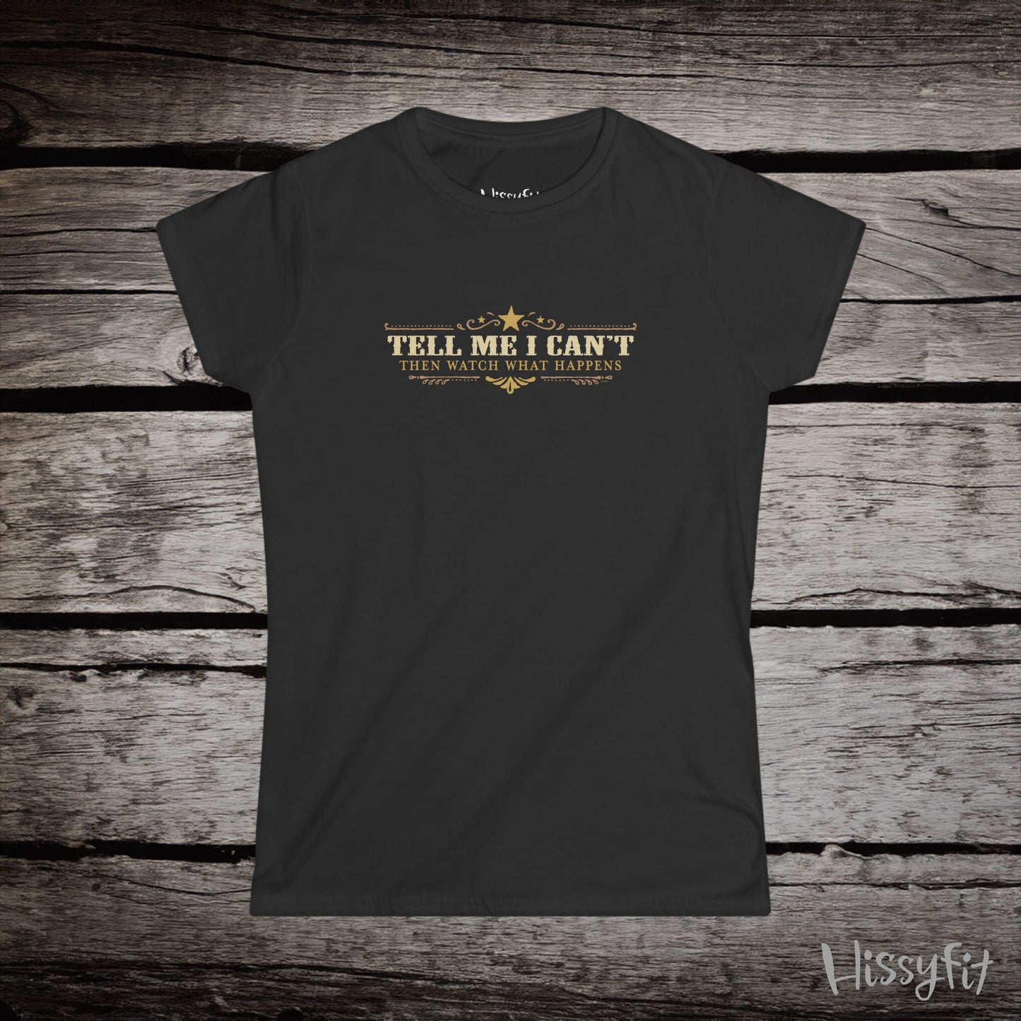 Black t-shirt with text 'Tell me I can't then watch what happens' on a wooden surface, featuring the brand 'Hissyfit'.