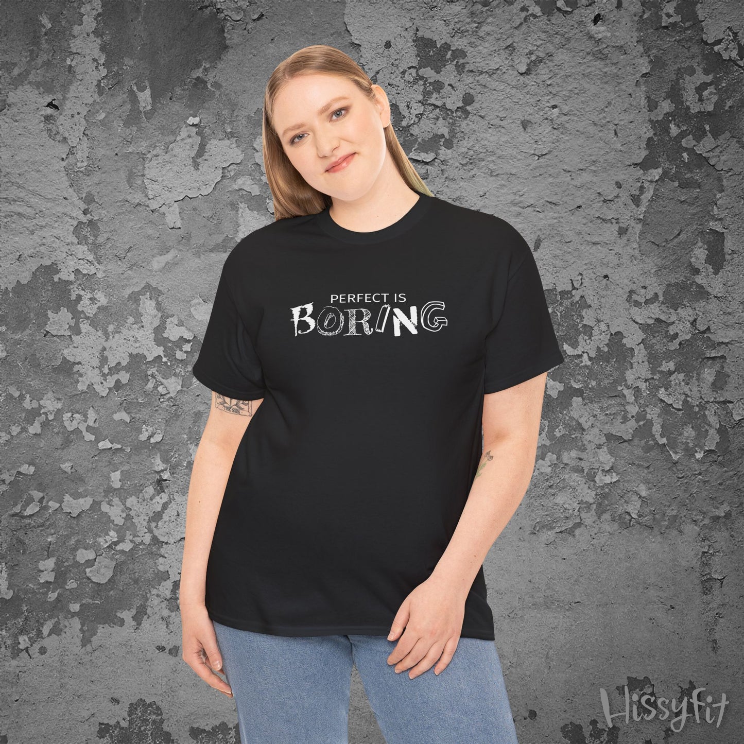 Person wearing a black t-shirt with 'PERFECT IS BORING' text against a textured gray background