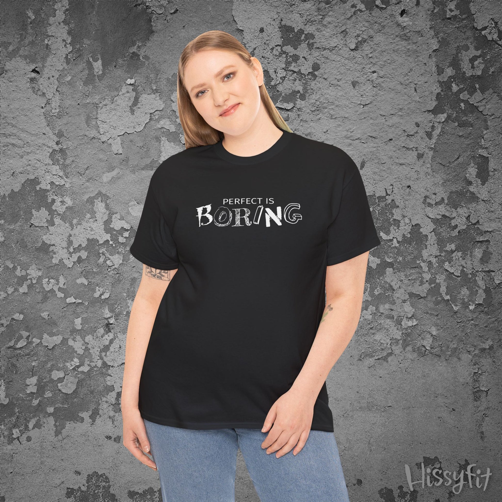Person wearing a black t-shirt with 'PERFECT IS BORING' text against a textured gray background