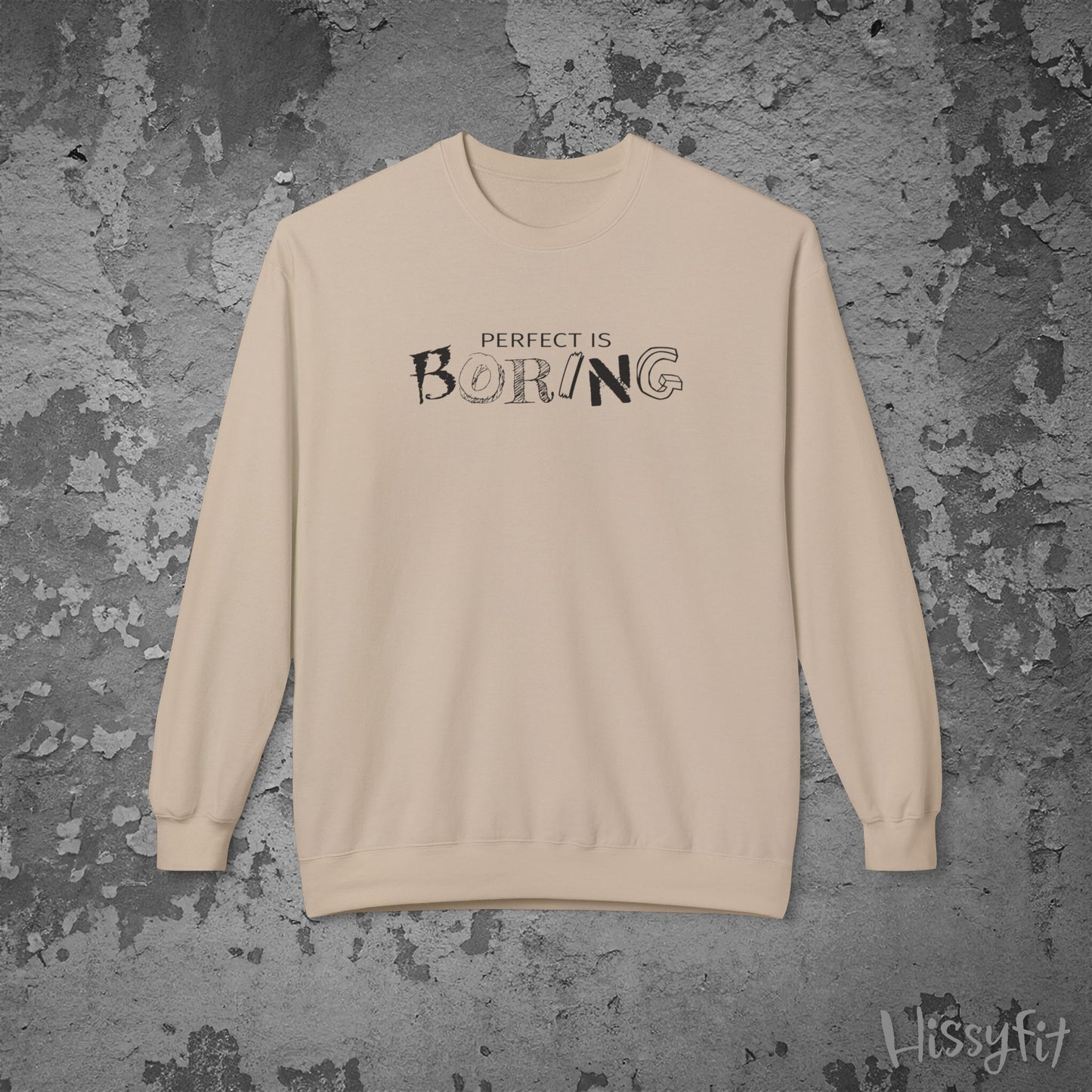 Beige sweatshirt with 'Perfect is Boring' text on a textured gray background