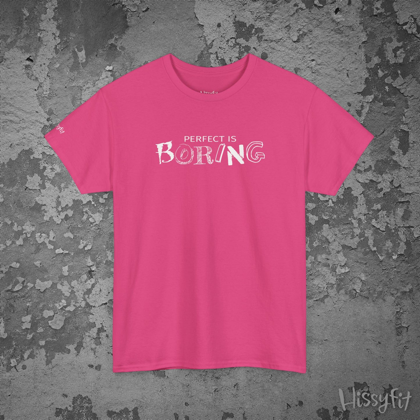 Pink t-shirt with 'PERFECT IS BORING' text on a textured gray background
