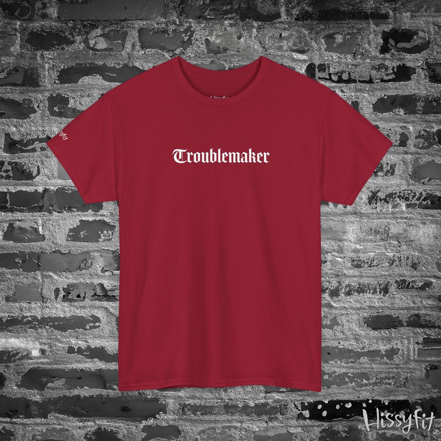 Red t-shirt with 'Troublemaker' text on a stone wall background