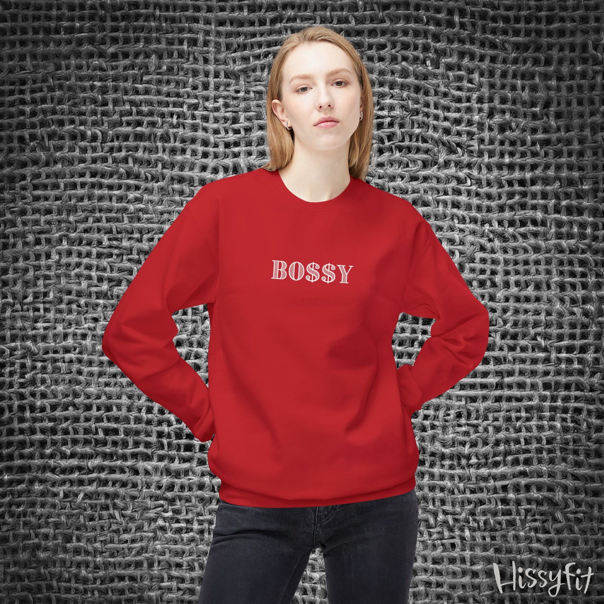 Person wearing a red sweatshirt with 'BOSSY' text against a textured gray background
