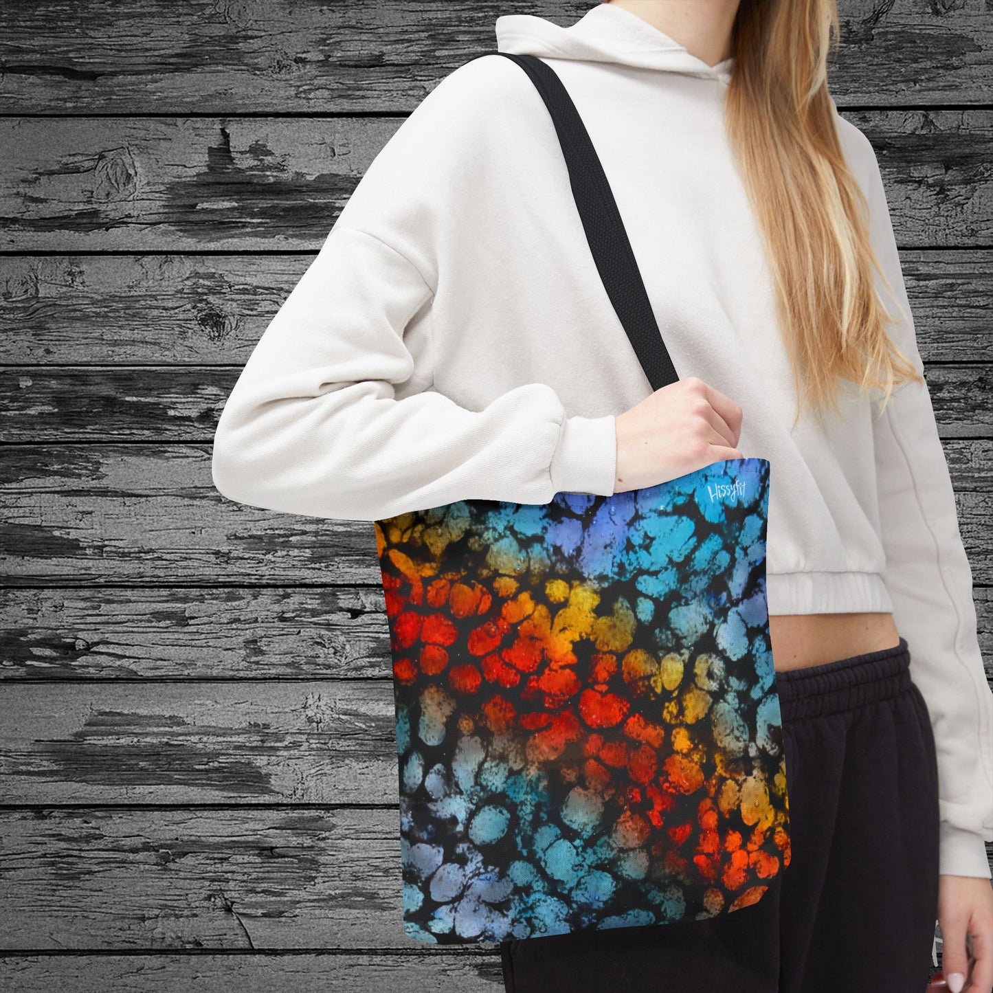 Person holding a colorful tote bag against a wooden background