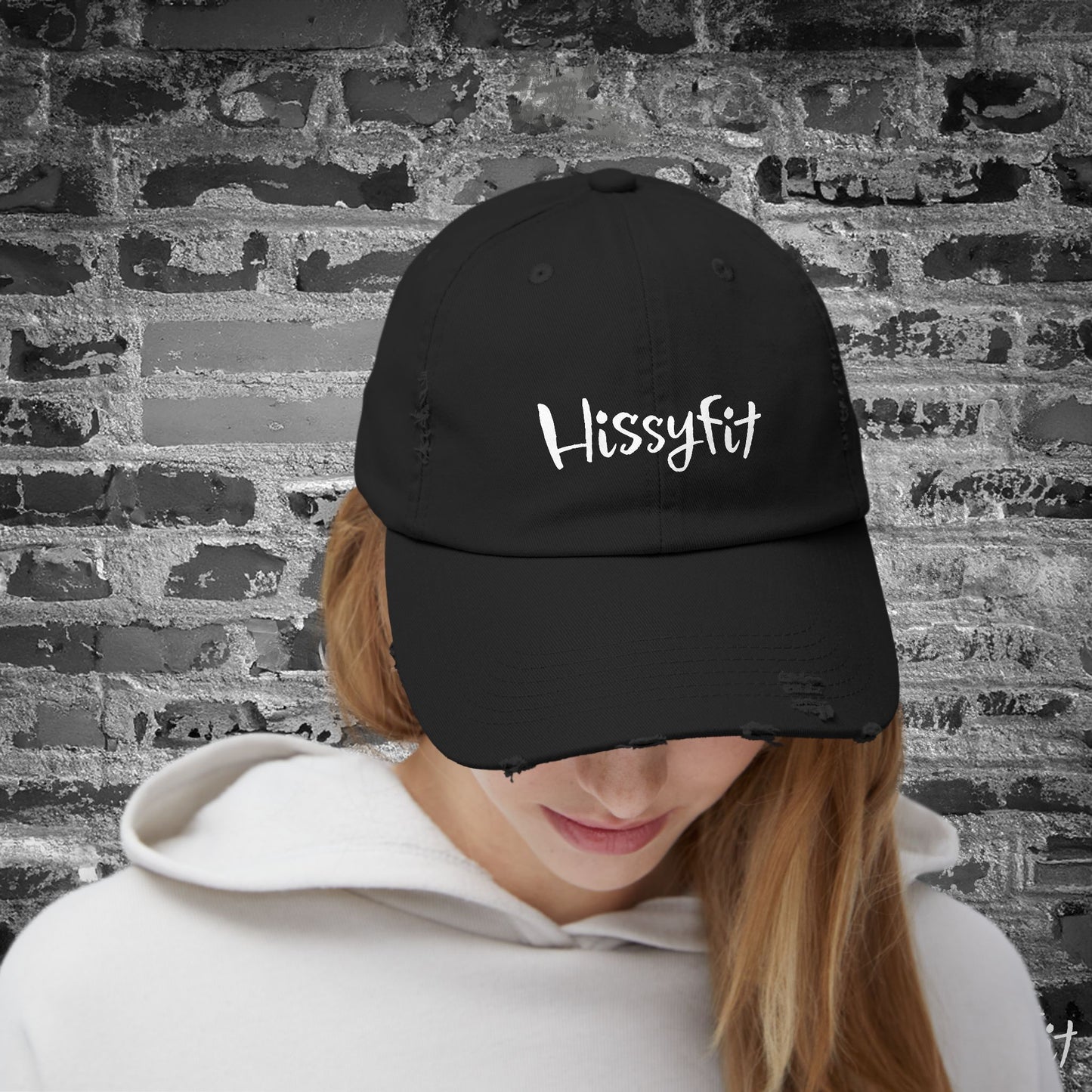 Person wearing a black cap with 'HissyFit' text against a textured wall background