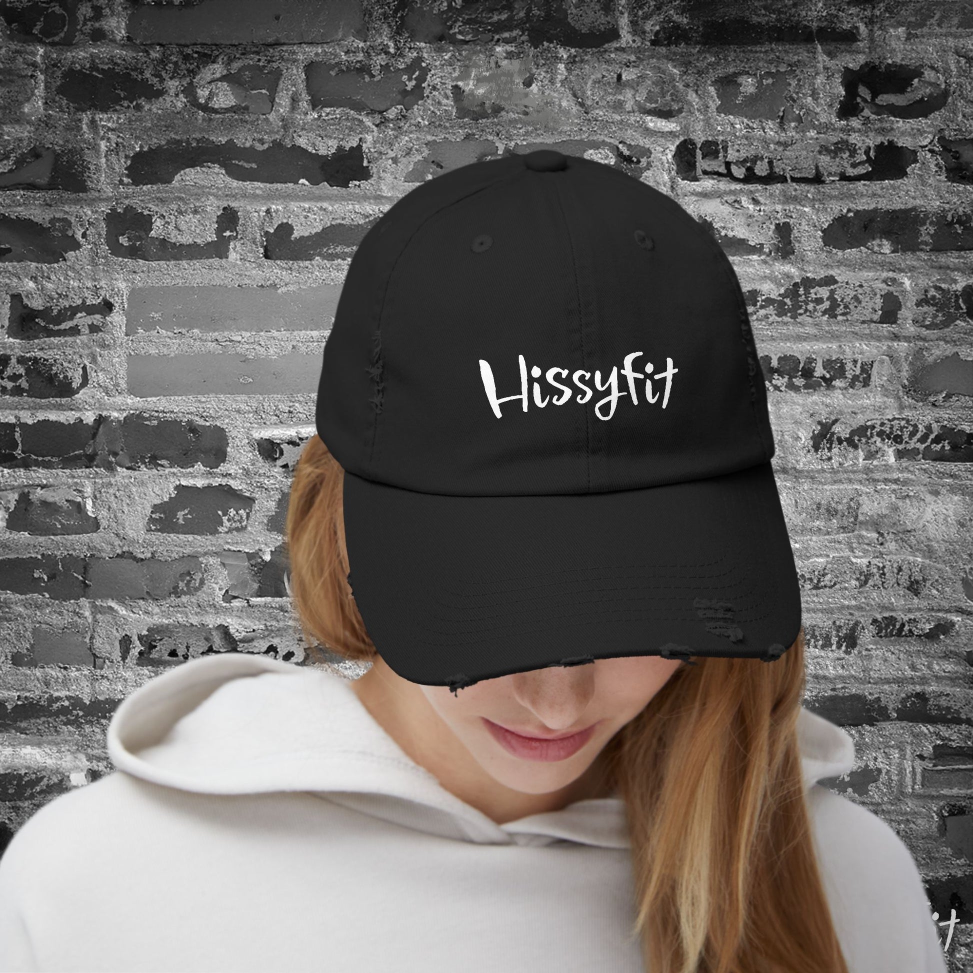 Person wearing a black cap with 'HissyFit' text against a textured wall background
