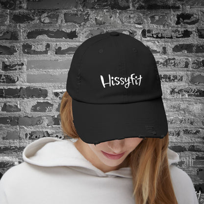 Person wearing a black cap with 'HissyFit' text against a textured wall background
