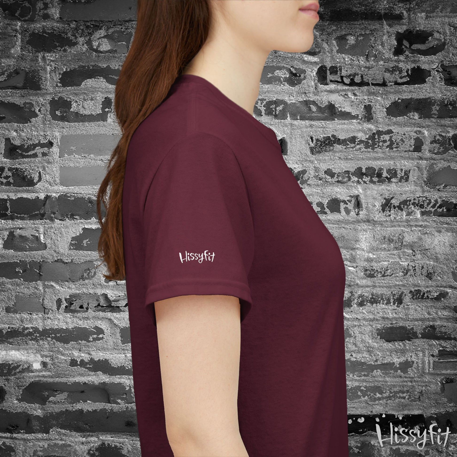 Person wearing a maroon t-shirt with 'Hissyfit' logo against a brick wall.