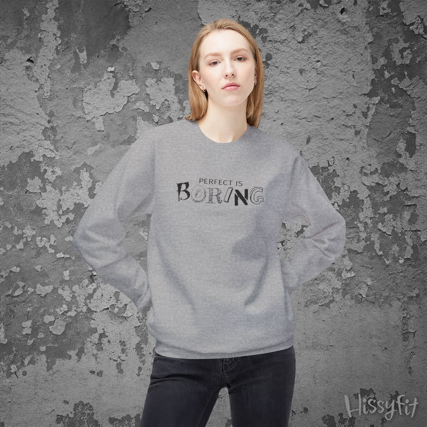 Person wearing a gray sweatshirt with 'PERFECT IS BORING' text against a textured gray background