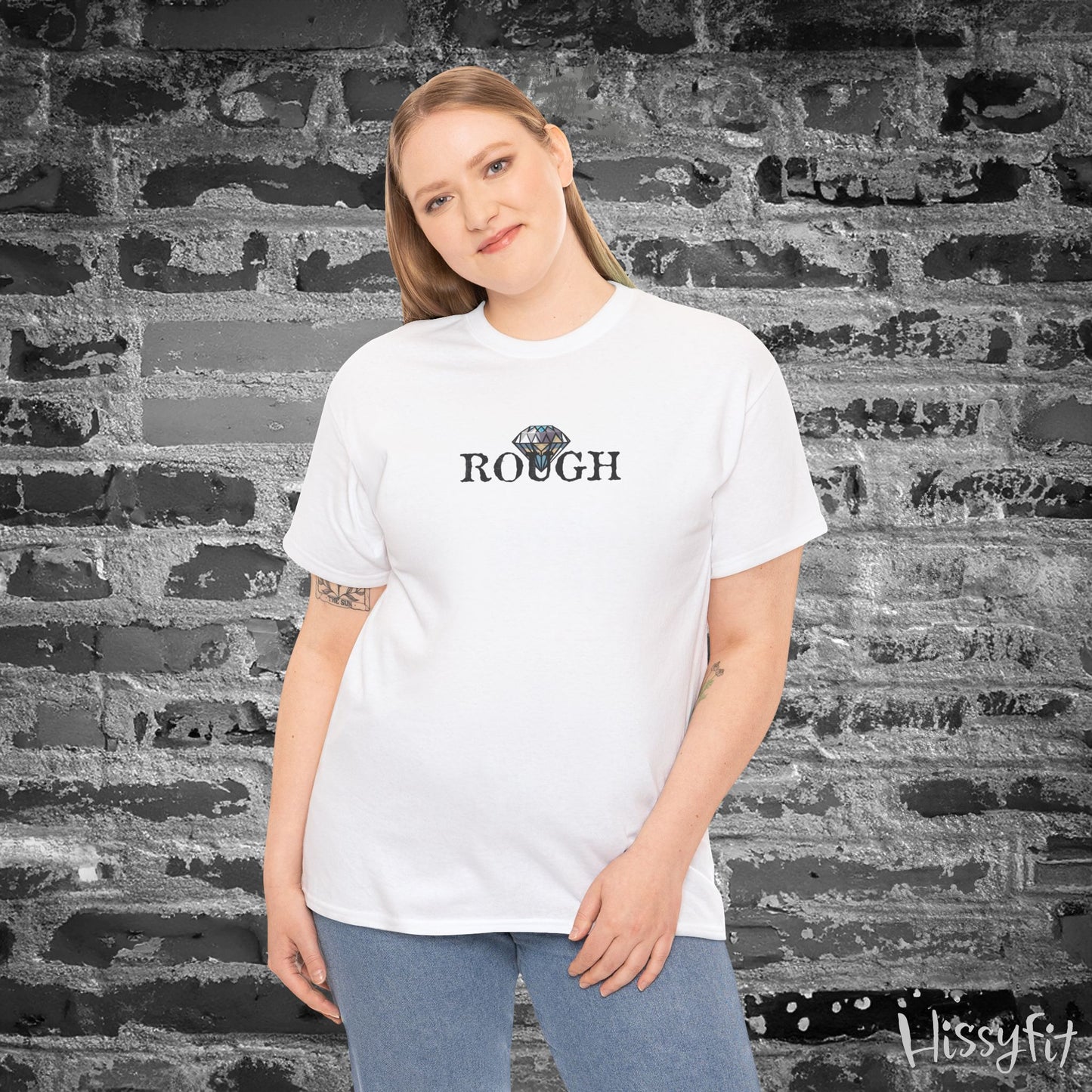 Person wearing a white t-shirt with a diamond graphic and 'ROUGH' text against a textured wall.