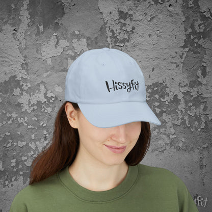 Person wearing a light blue cap with 'Hissyfit' text against a textured gray wall.