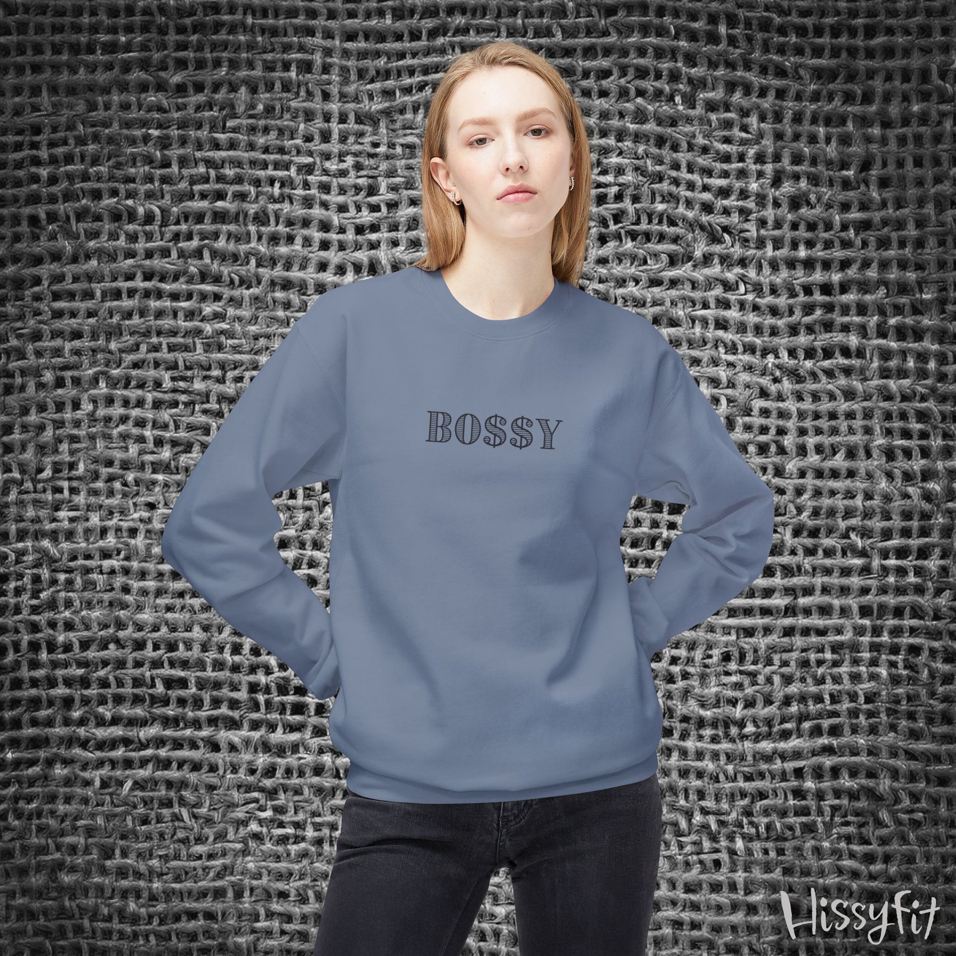Person wearing a blue sweatshirt with 'BOSSY' text against a textured gray background