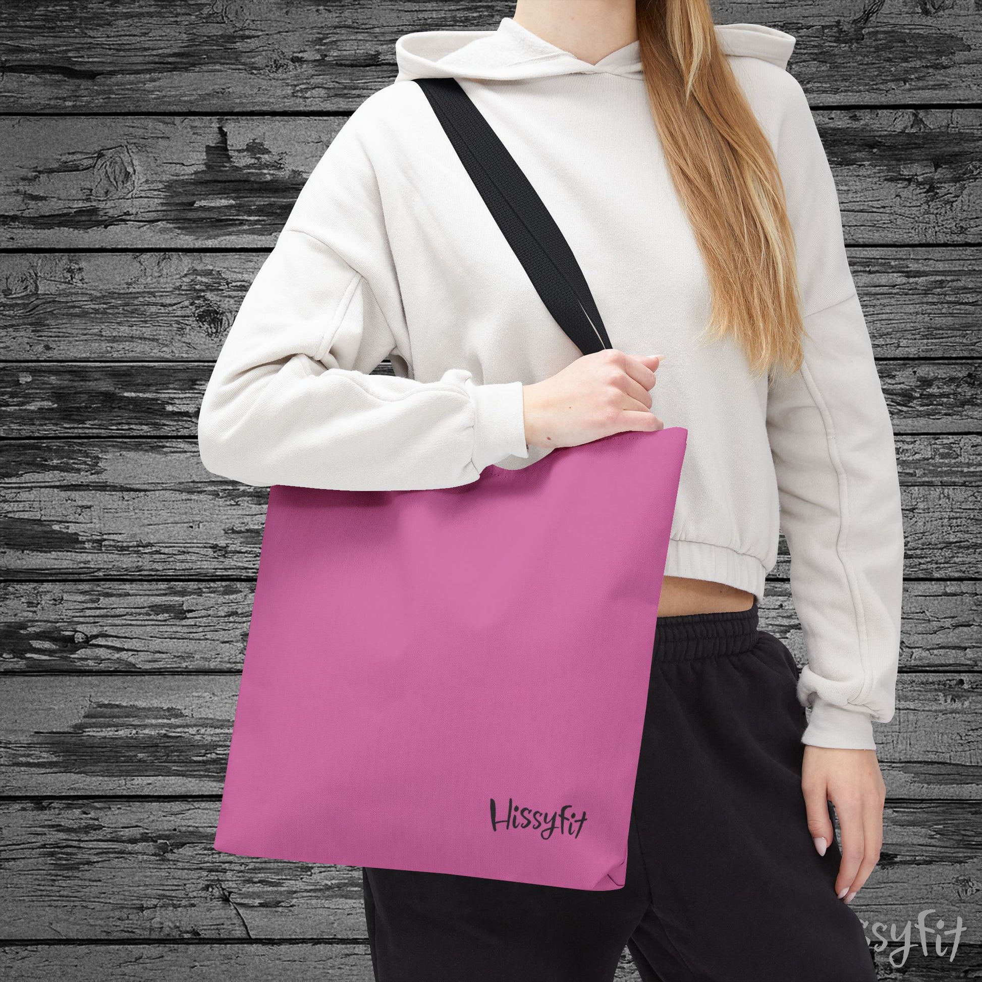 Person holding a pink tote bag with 'Hissyfit' branding against a wooden background