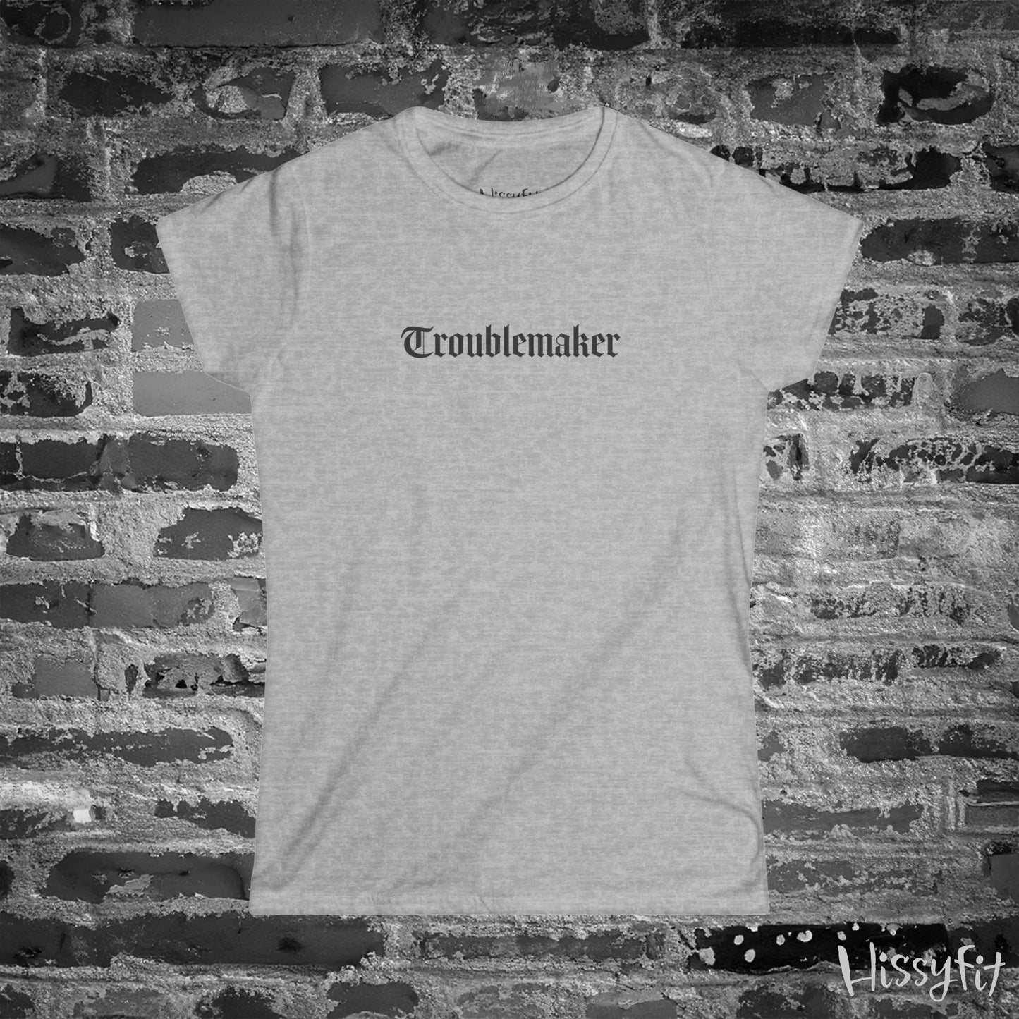 Gray t-shirt with 'Troublemaker' text on a brick wall background