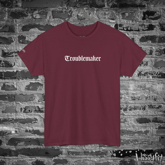 Maroon t-shirt with 'Troublemaker' text on a stone wall background