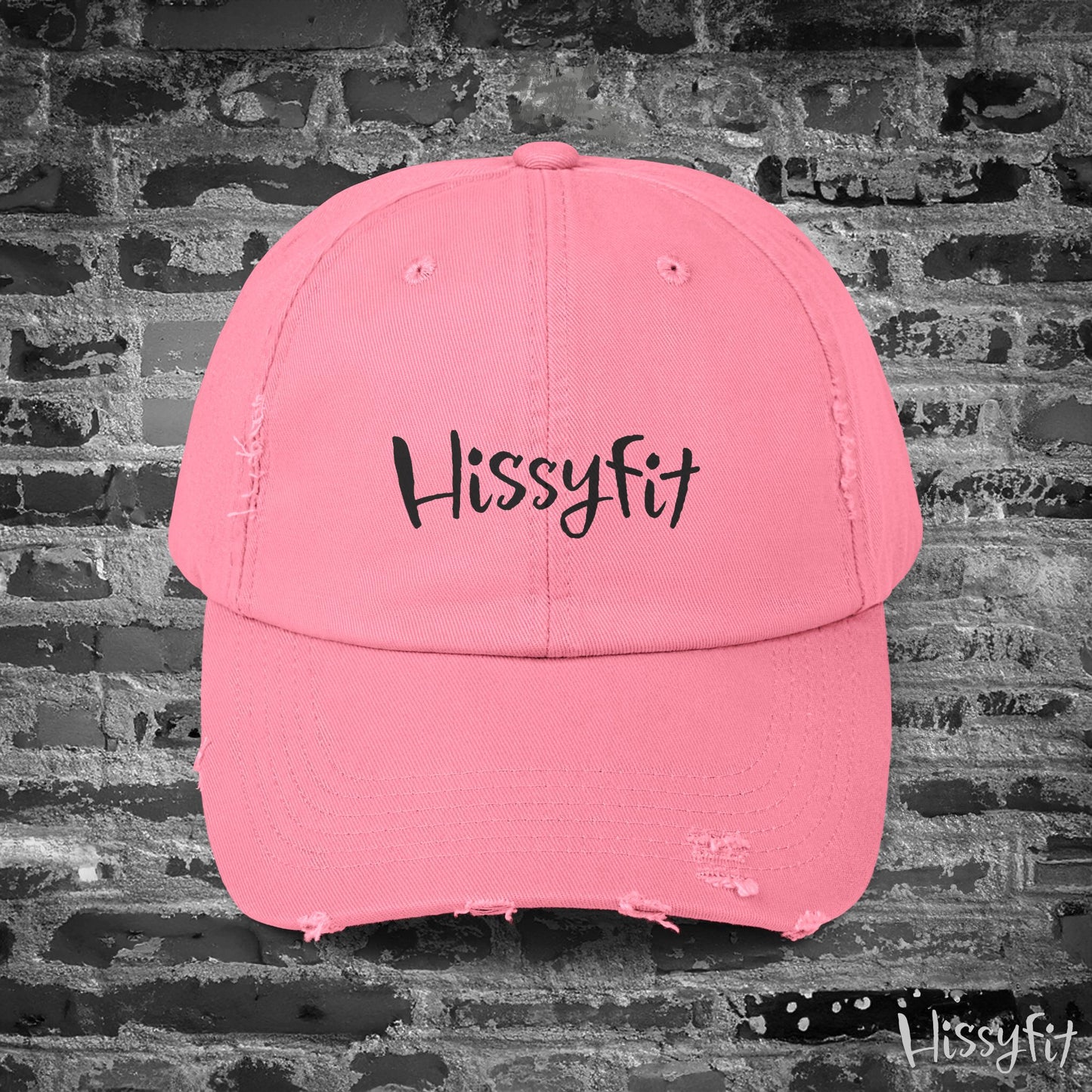Pink cap with 'Hissyfit' text on a brick wall background