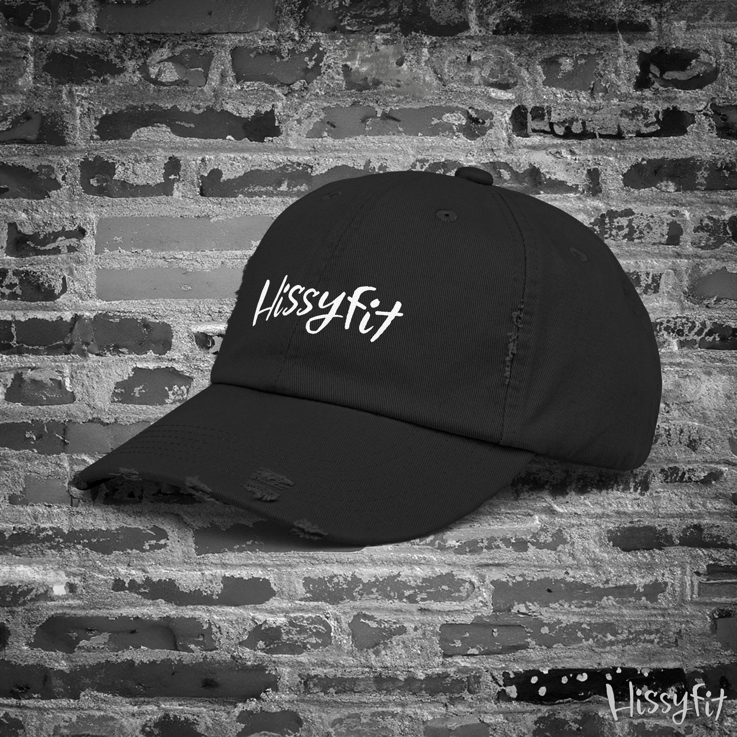 Black cap with 'Hissyfit' logo on a brick wall background