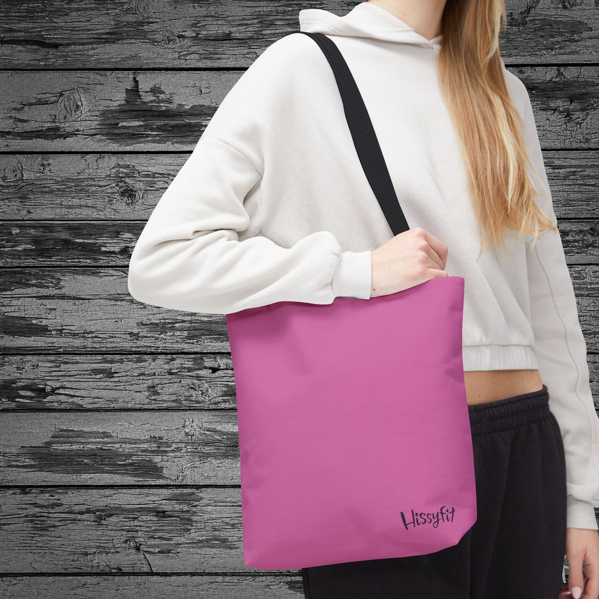 Person holding a pink tote bag with 'Hissyfit' branding against a wooden background