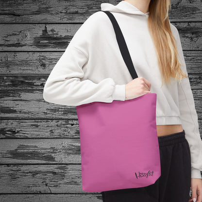Person holding a pink tote bag with 'Hissyfit' branding against a wooden background