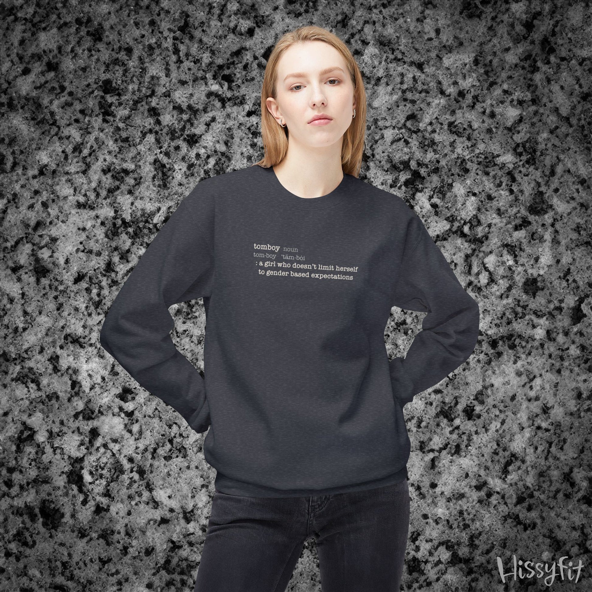 Person wearing a dark grey sweatshirt with text definition of "Tomboy" on a gray and black speckled background