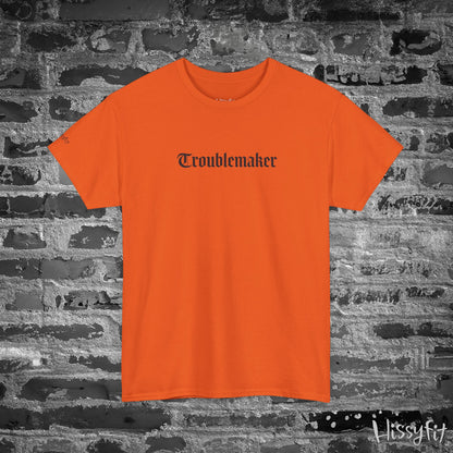 Orange t-shirt with 'Troublemaker' text on a brick wall background