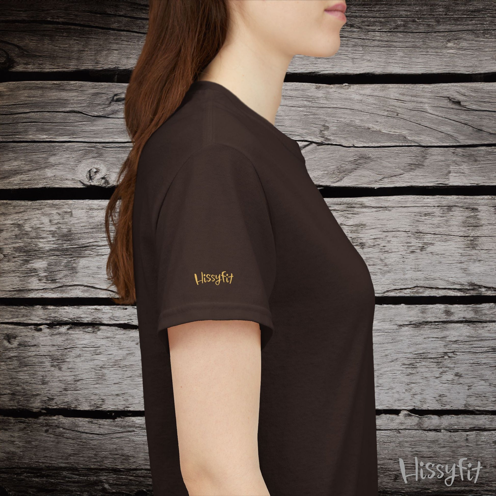 Person wearing a brown t-shirt with 'Hissyfit' logo against a wooden background