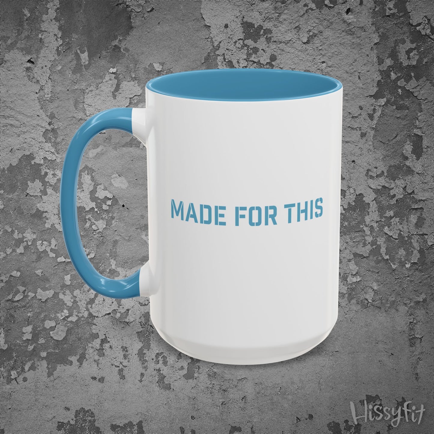 White mug with blue interior and handle on a textured gray background, featuring 'MADE FOR THIS' text.