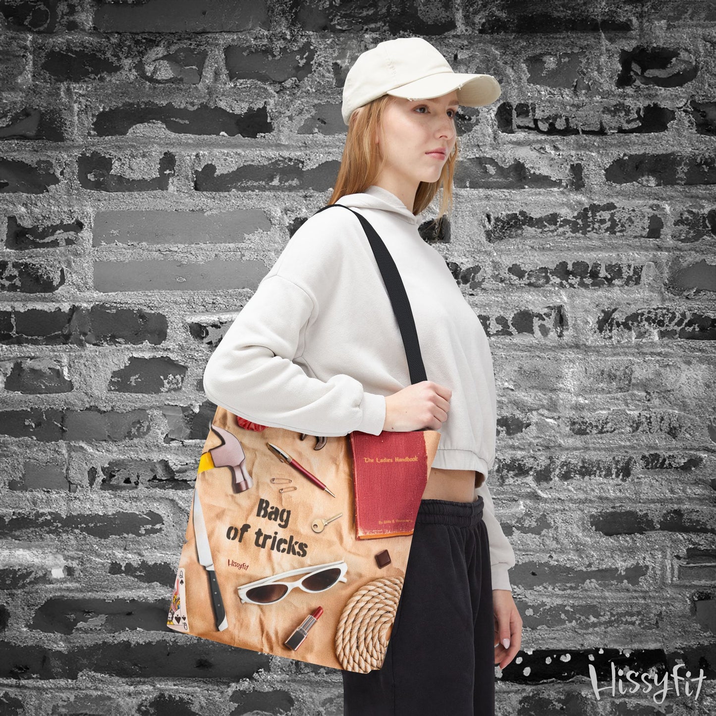Person holding a tote bag with decorative items and text 'Bag of tricks' against a textured wall background