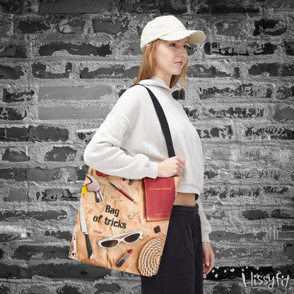 Person holding a tote bag with decorative items and text 'Bag of tricks' against a textured wall background