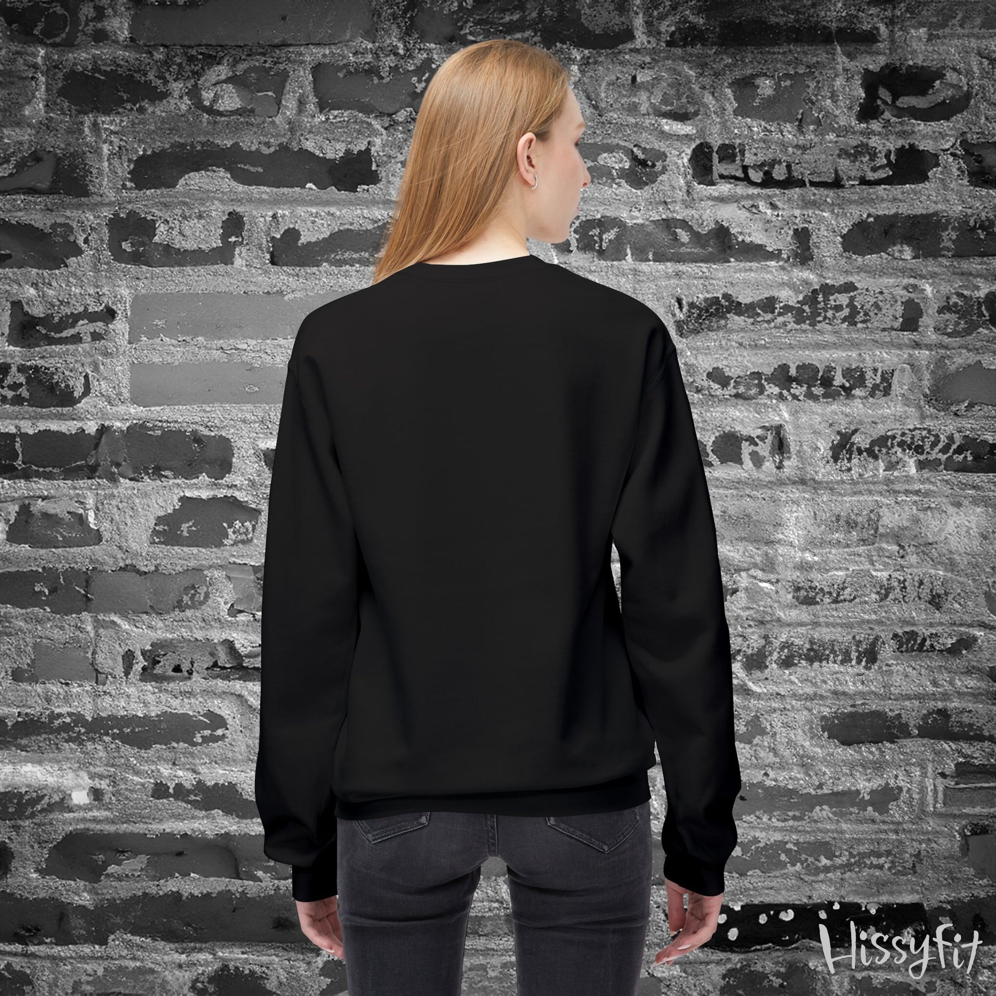 Person wearing a black sweatshirt in front of a textured brick wall