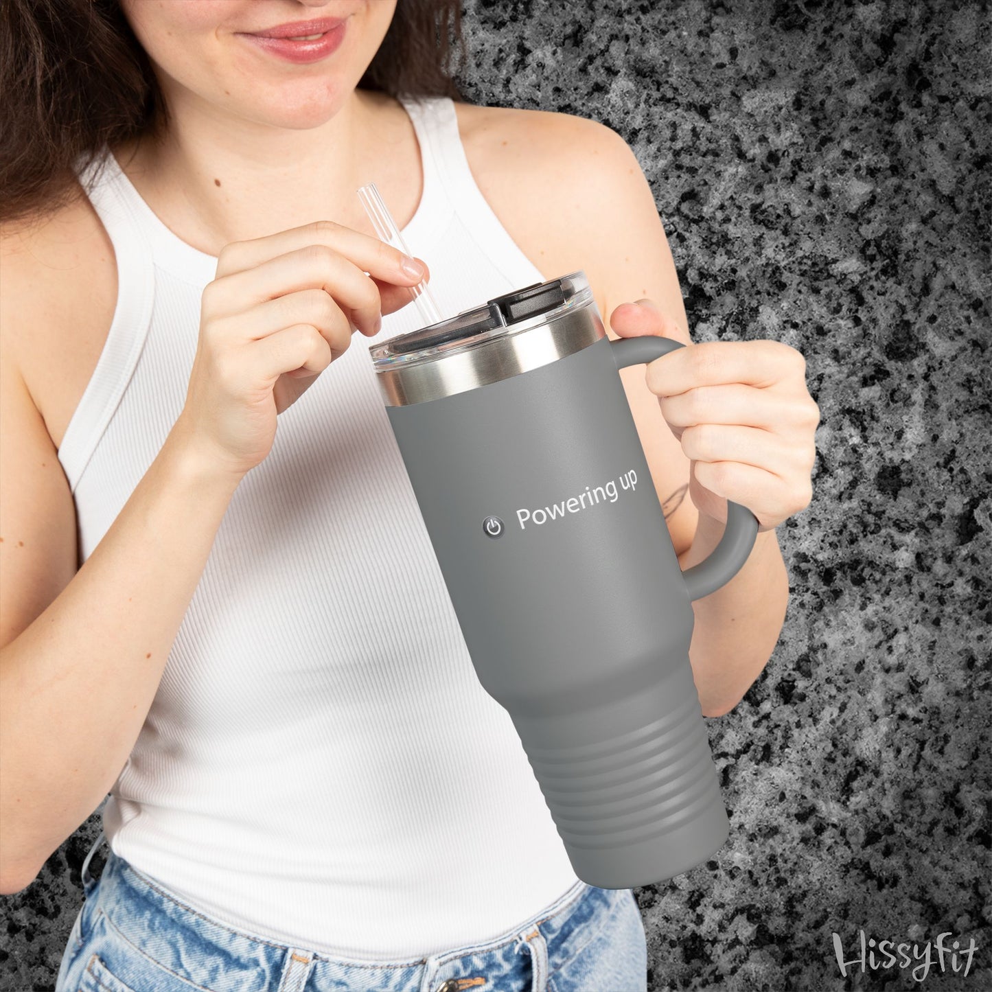 Person holding a gray travel mug with 'Powering up' text against a dark granite background