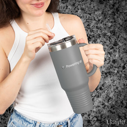 Person holding a gray travel mug with 'Powering up' text against a dark granite background