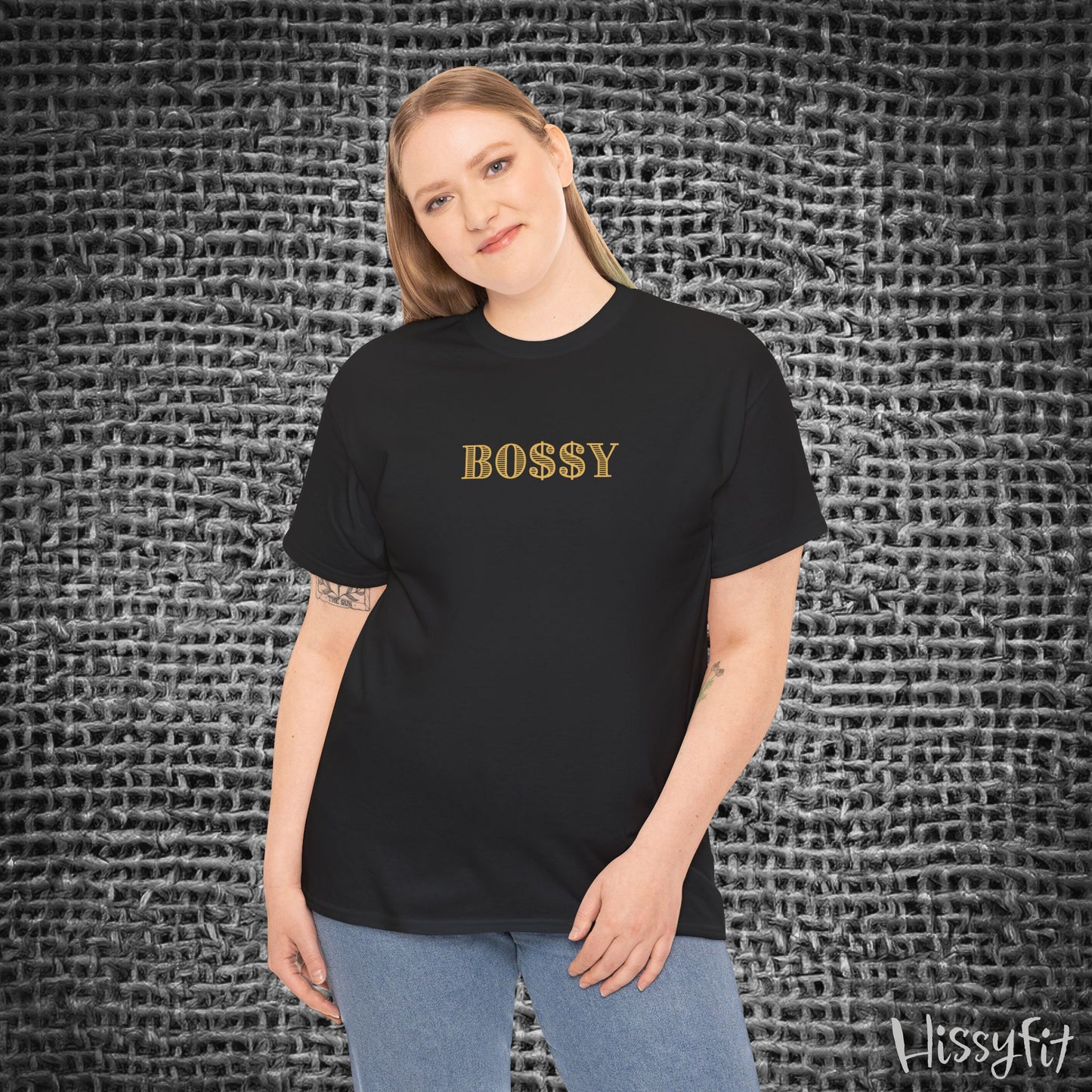 Person wearing a black t-shirt with 'BOSSY' text against a textured gray background