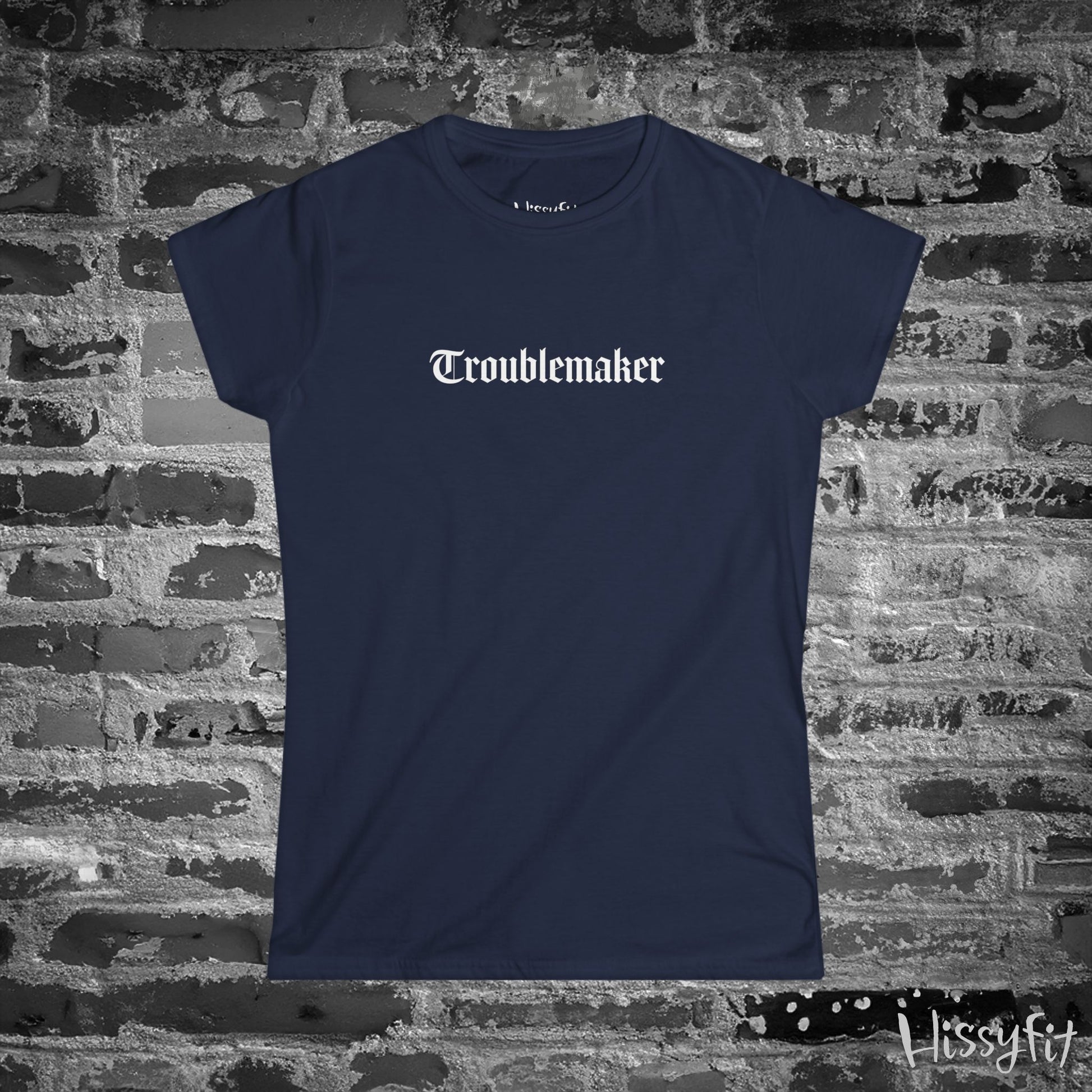 Navy blue t-shirt with 'Troublemaker' text on a brick wall background