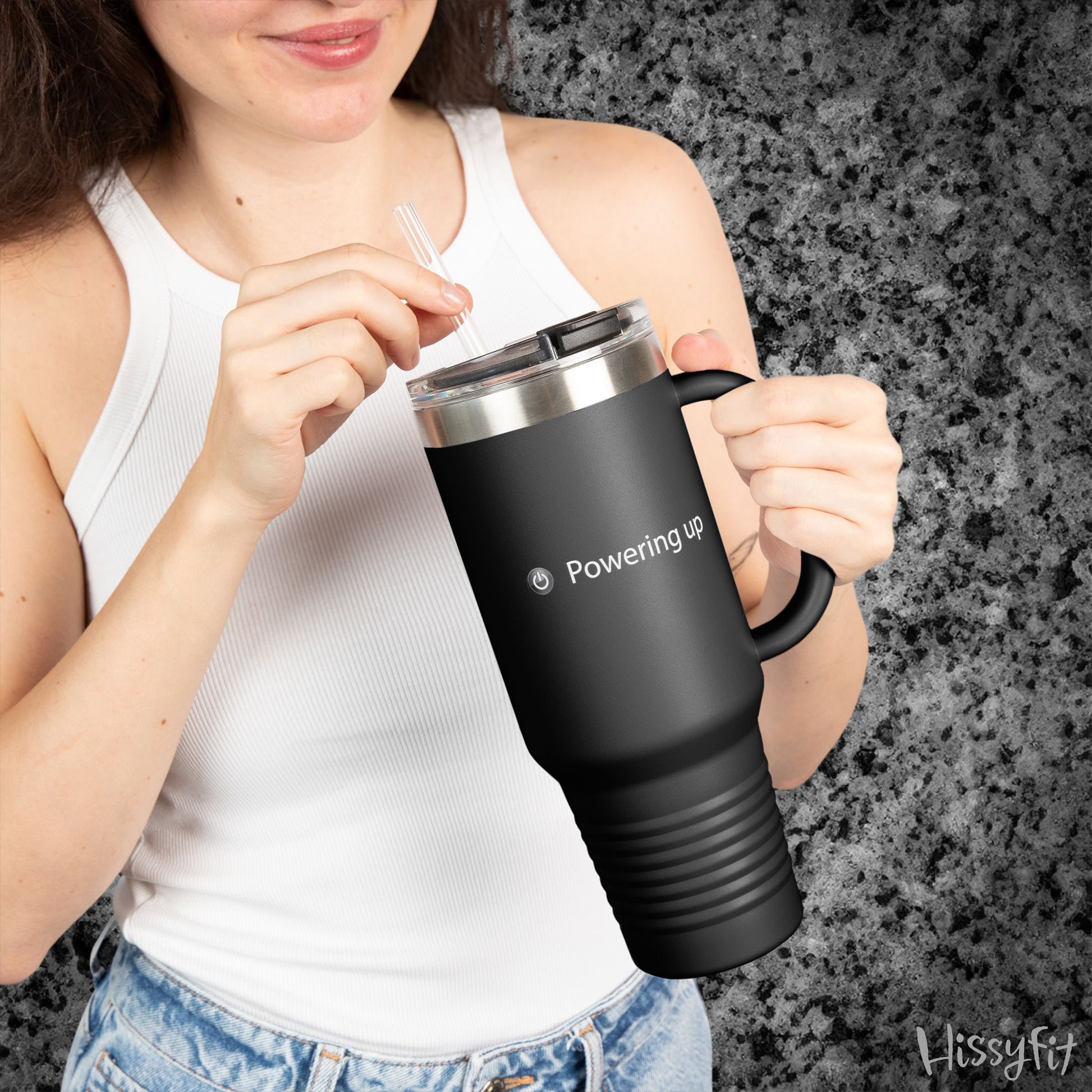 Person holding a black travel mug with 'Powering up' text against a gray background