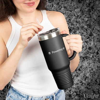 Person holding a black travel mug with 'Powering up' text against a gray background