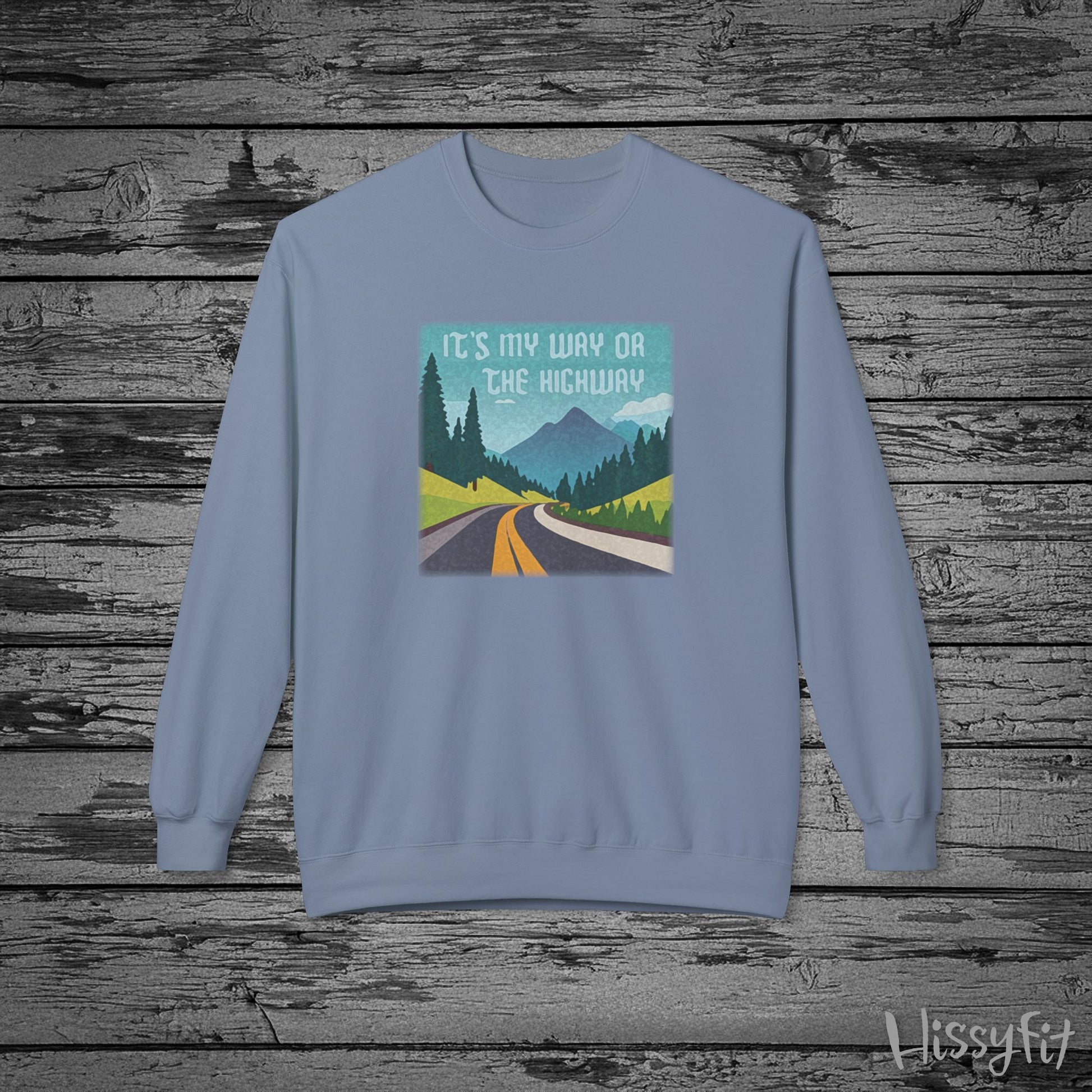 Light blue sweatshirt with a graphic design of a road and "It's my way or the highway" text on a wooden background
