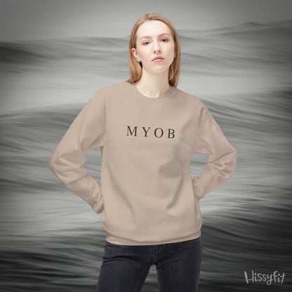Person wearing a beige sweatshirt with 'MYOB' text against a gray background