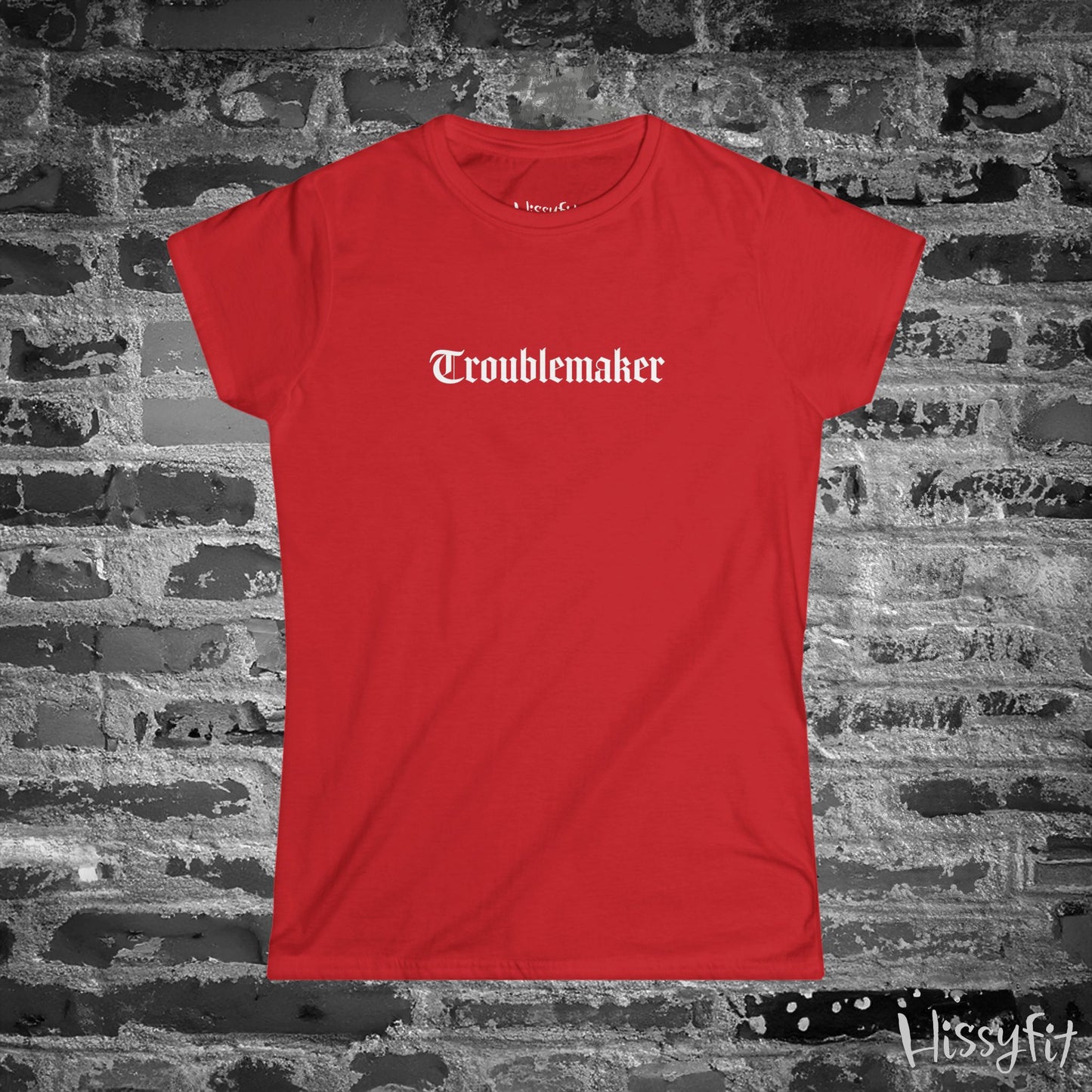 Red t-shirt with 'Troublemaker' text on a brick wall background