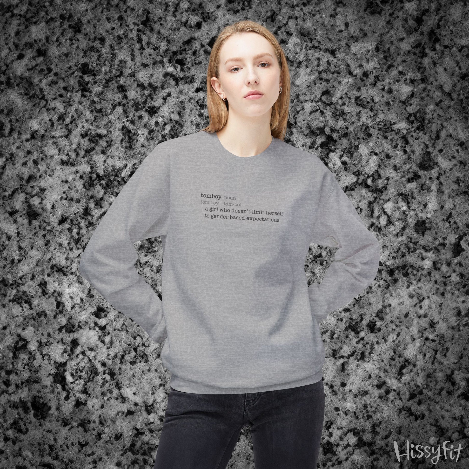 Person wearing a gray sweatshirt with text definition of "Tomboy" on a gray and black speckled background