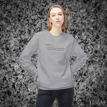 Person wearing a gray sweatshirt with text definition of "Tomboy" on a gray and black speckled background
