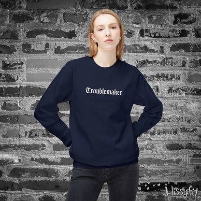 Person wearing a navy blue sweatshirt with 'Troublemaker' text against a textured brick wall.