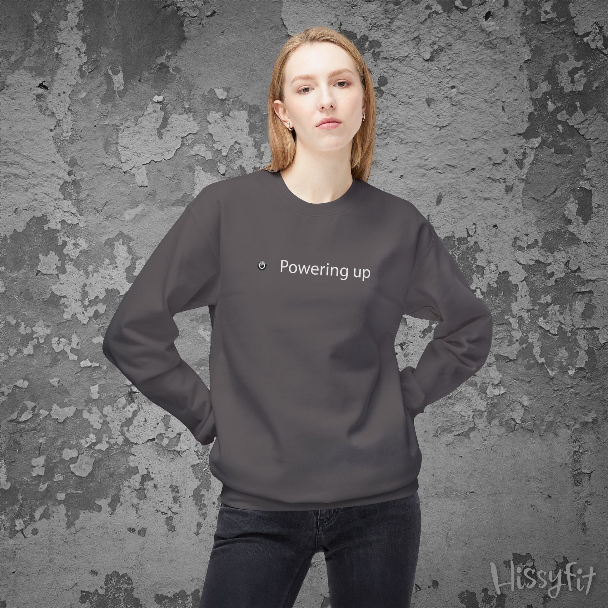 Person wearing a dark gray sweatshirt with 'Powering up' text against a textured gray background
