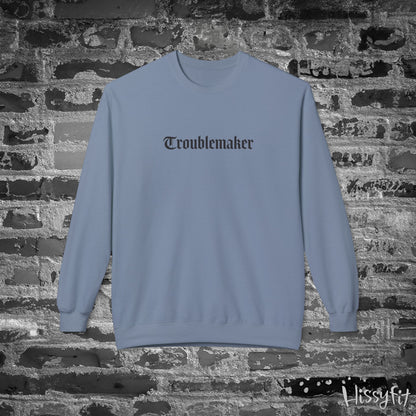 Blue sweatshirt with 'Troublemaker' text on a brick wall background